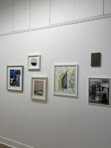 Several contemporary paper art pieces are hanging on a white wall.