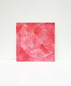 A red square artwork placed against a white background. The surface shows dense, branching textures and lighter areas, resembling liquid spread patterns or organic veins.