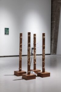 An installation on a wooden frame with a telephone at the centre, surrounded by string and paper-pulp forms with a gritty, sand-like surface, placed on the gallery floor.