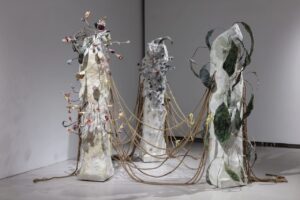 Several paper-pulp and hanji structures are linked by ropes and ribbons that hang and pull across space, forming an expandable installation.