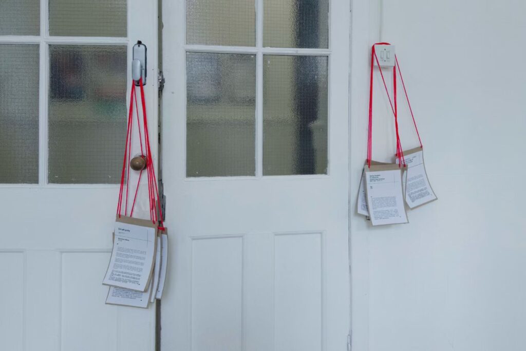 Installation view of Our Shell, showing hanging label design in relation to the gallery doorway, Summerhall, Edinburgh, 2026. Photograph by Luosijie Ding.