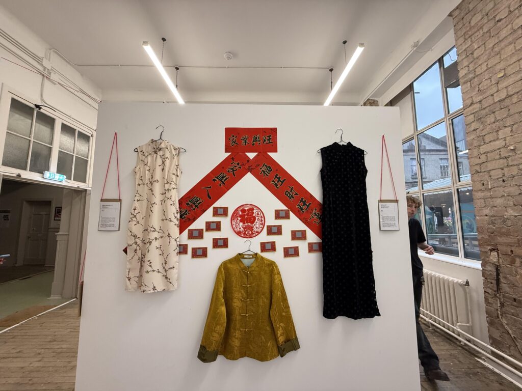 Installation view of Our Shell, showing garment installation and wall arrangement, Summerhall, Edinburgh, 2026. Photograph by Hazel Ren.