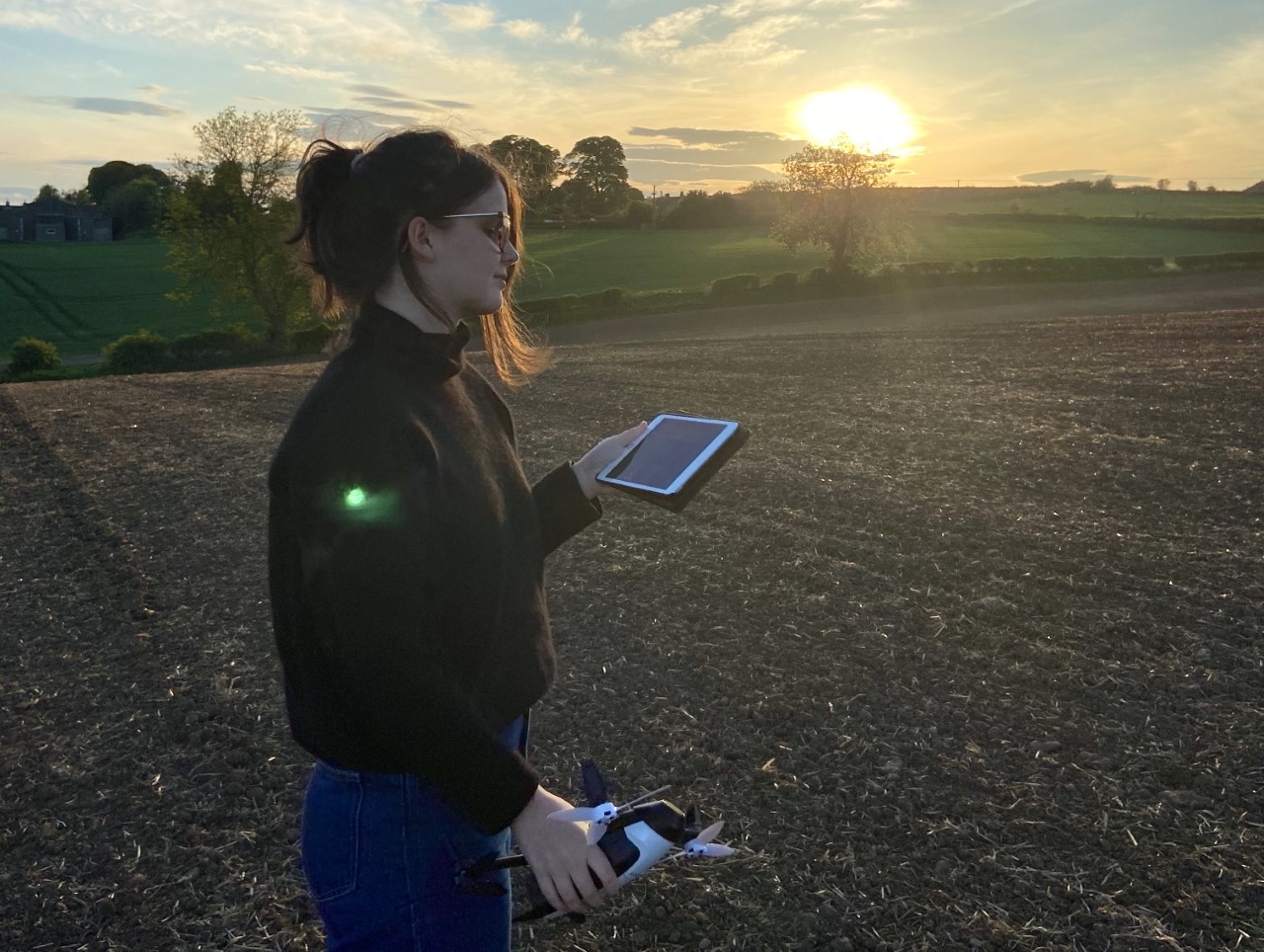 Kezia in a field holding a drone and tablet.