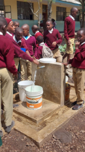 Clean water is pumped from the well to the delight of students
