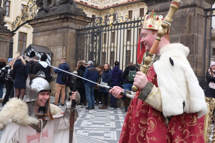 A student dressed as a king pretends to knight another student dressed as a knigh