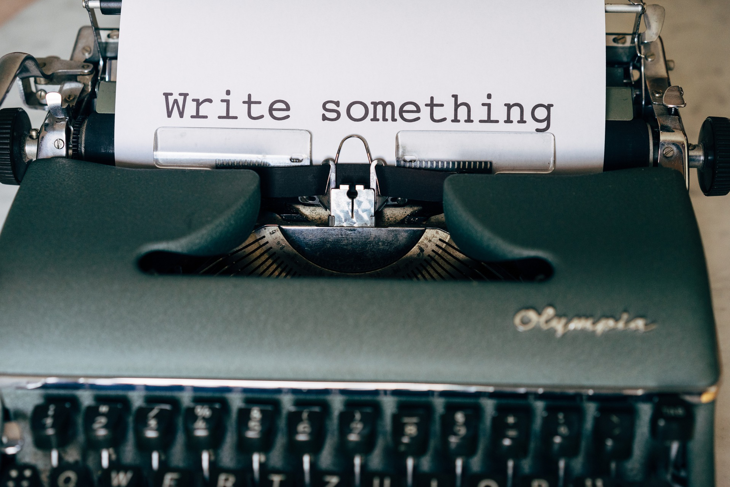 An image of a typewriter with the words write something on the paper