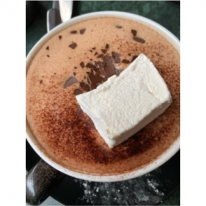 A mug of hot chocolate with a large marshmallow floating in it. It looks delicious!