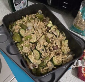 Food in a baking tray resting on top of another tray on a kitchen counter.