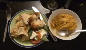 A plate with salad and bread on a table next to a bowl of risotto.