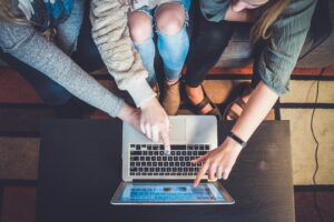 Three people pointing to a laptop screen