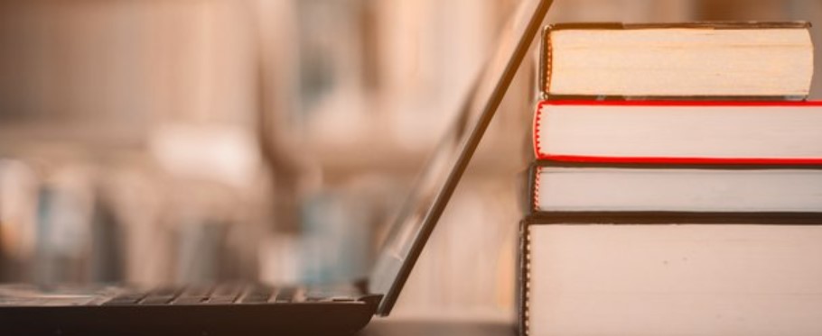 Image of a laptop leaning against a stack of books