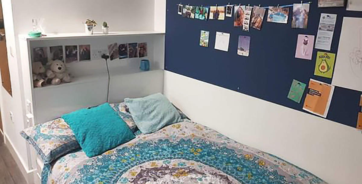 View of a student's accommodation room with pin board and bed spread.