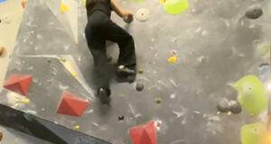 A student is bouldering on a climbing wall.