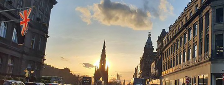 View of Princes Street with the sun behind the Scott Monument