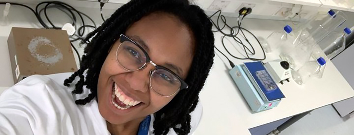 A scientist smiles at the camera in her lab.