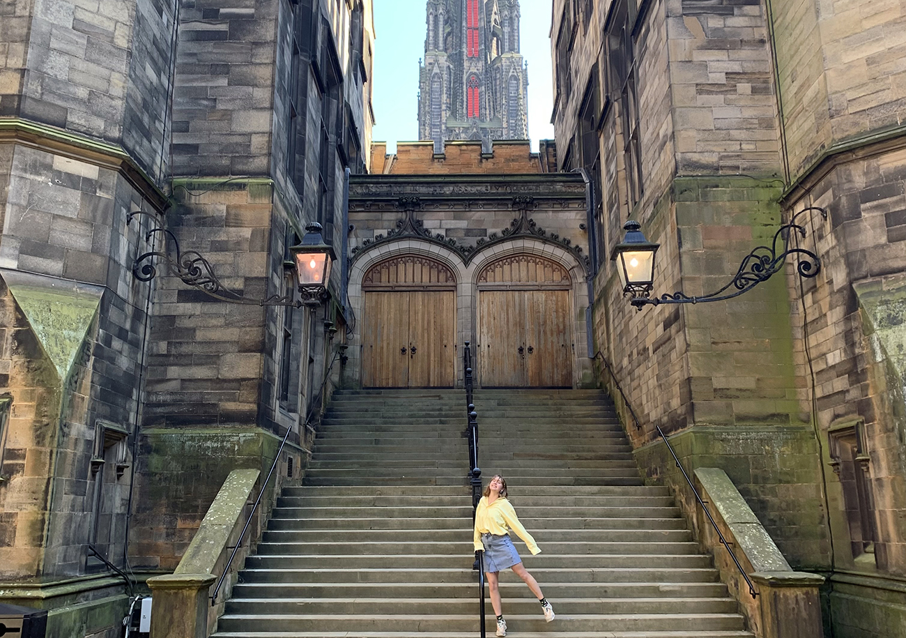 A student stands at the bottom of the steps to the grand entrance of New College.