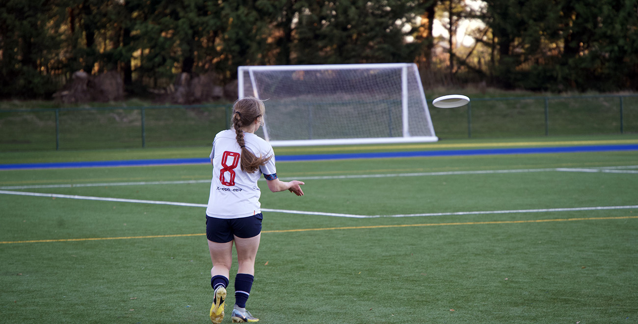 Student in a team sports kit throwing a frisbee