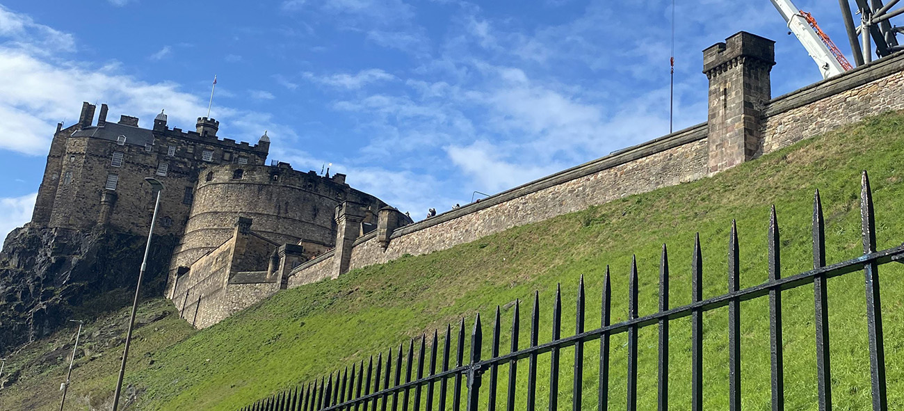 View of railings and Edinburgh Castle on a sunny day.