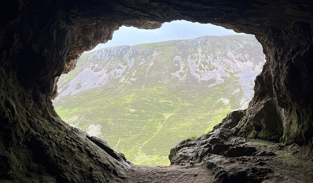 View from inside a cave looking back at the opening and the hills beyond.