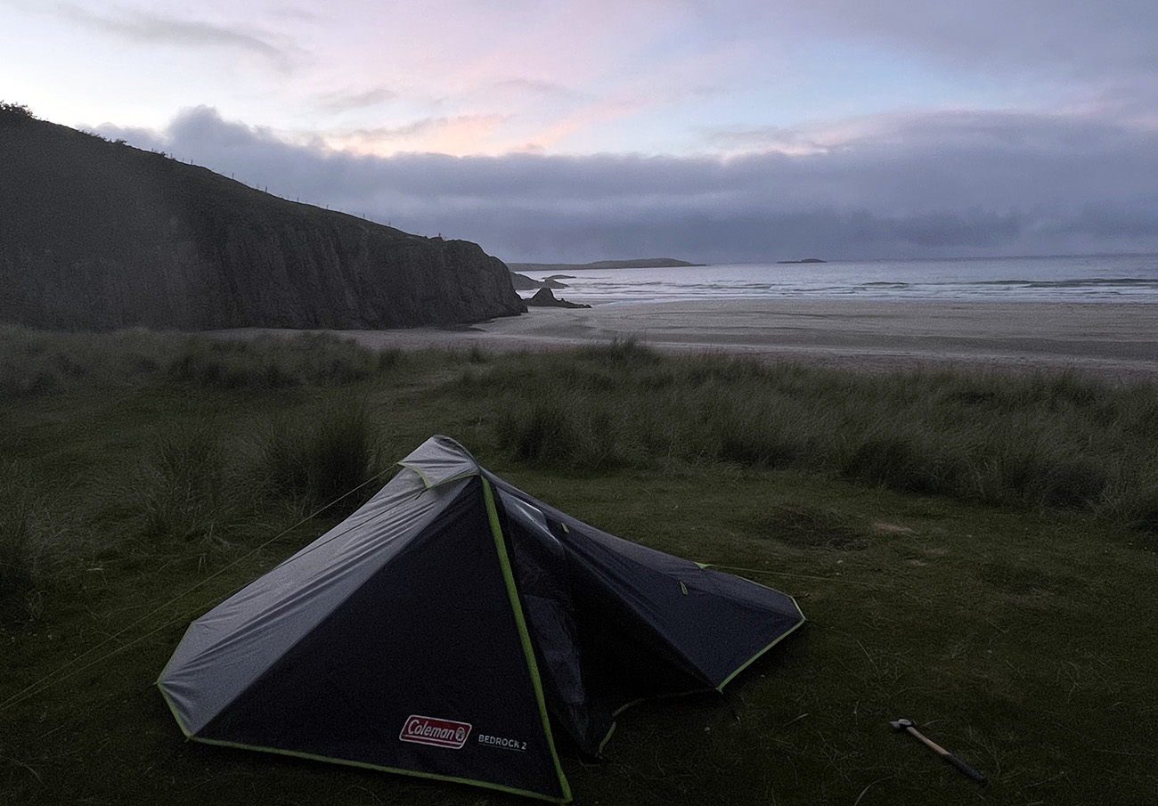 View of a tent and beach with a dawn sky above.