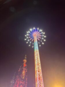 A brightly illuminated Starflyer ride soaring beside the Scott Monument in Edinburgh.