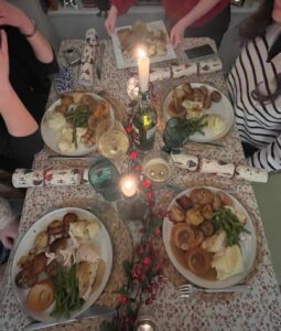 A traditional Christmas dinner on a table along with Christmas crackers and candles.