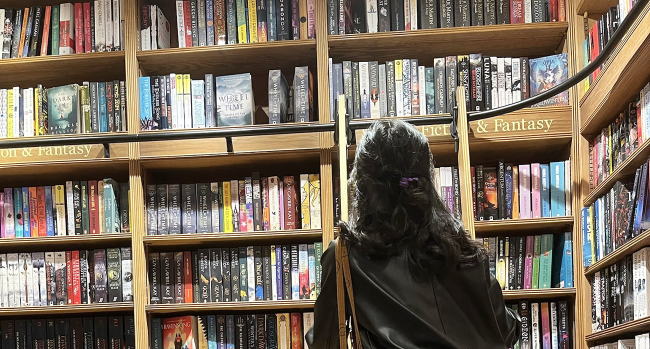 A student on a ladder within a book shop.