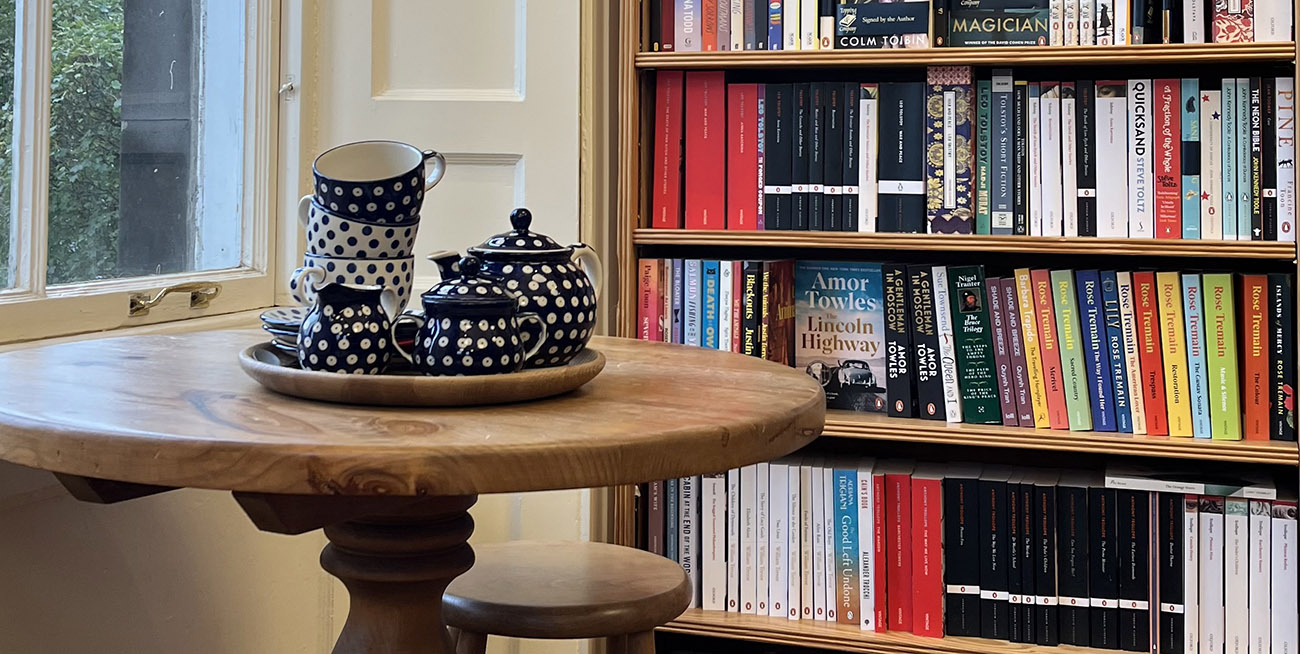 View of a tea set on a table within a book shop.