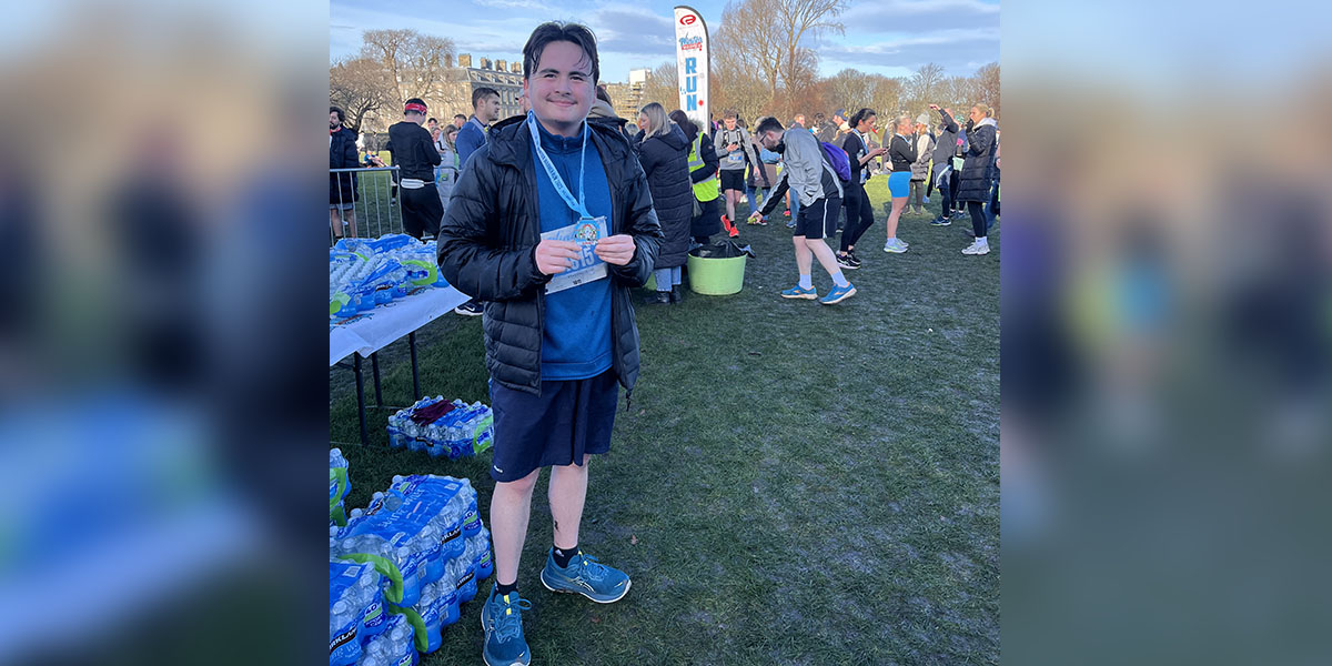Graham stands at the end of a fun run, displaying his medal.