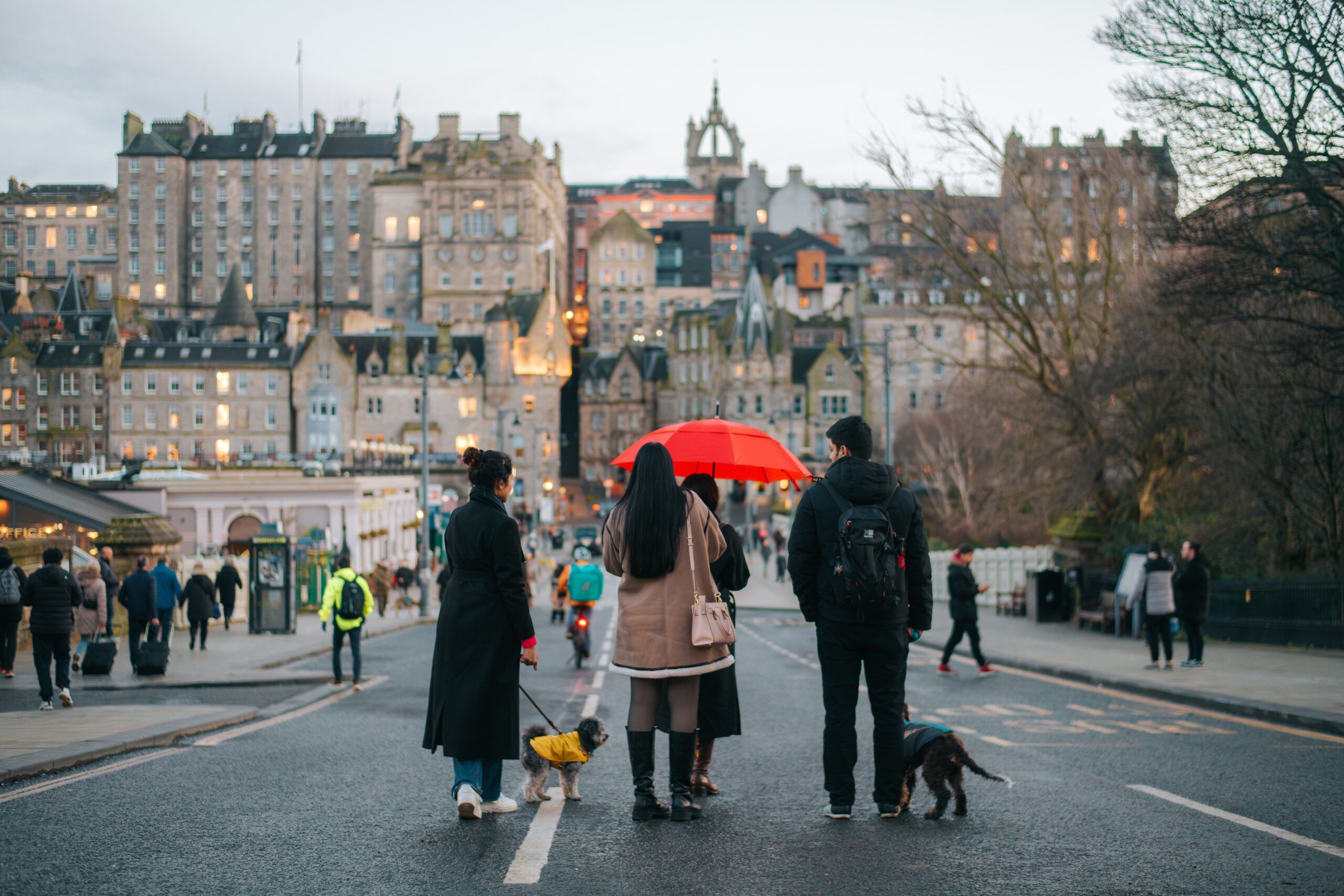 A group of people standing with an umbrella looking at Old Town skyline in Edinburgh
