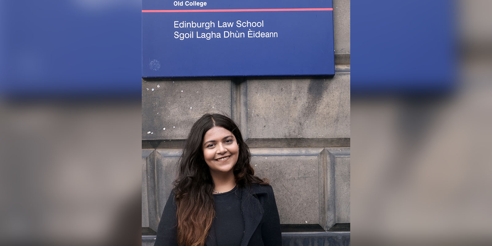 Narayani stands in front of a sign for the Edinburgh Law School.