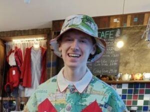 A person smiling for a photo with a hat and polo shirt on.