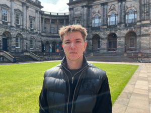 A person posing for a photograph in the courtyard of Old College.