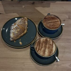 Two cups of coffee and a pastry.