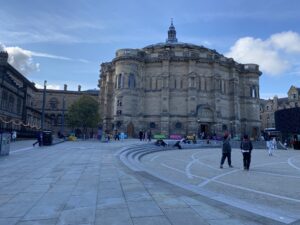 A couple of people walk past the exterior of McEwan Hall in Edinburgh. 