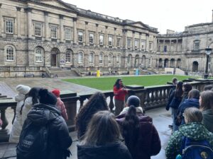 Student ambassador Aagoon giving a campus tour in the Old College Quad. Aagoon talks to a crowd of tour attendees. 