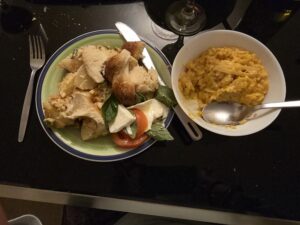 A plate with salad and bread on a table next to a bowl of rissotto.