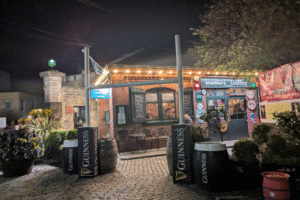 The exterior of a pub, furnished with branded decor and shrubbery.
