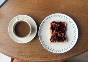 Aerial view of a plate with toast covered in homemade blueberry jam and a cup and saucer.