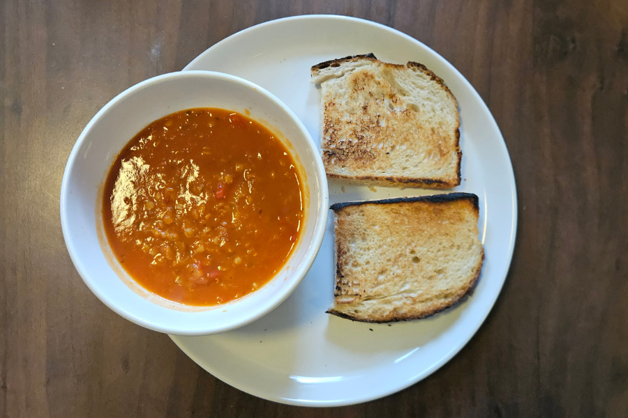 A bowl of soup and toasted bread on a plate.