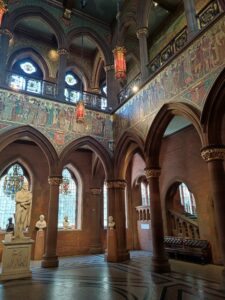 Interior of the Great Hall in Scottish National Portrait Gallery, featuring Intricate Victorian details, stained glass, fresco decorations and an astrological ceiling.