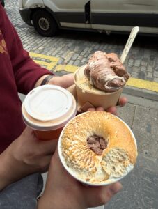 Two sets of hand hold a hot string and tubs of gelato.