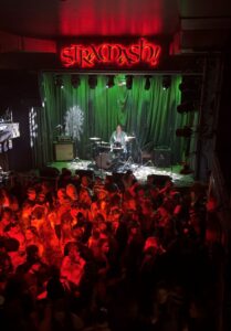 Drummer on stage at Stramash. A large crowd of people stand in front of the stage.