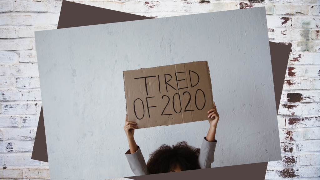 person holding a sign saying 'tired of 2020'