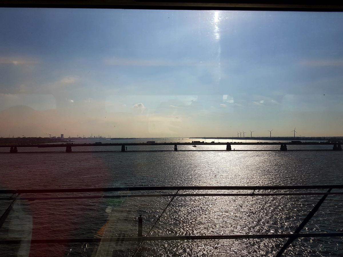 A large body of flat water stretching into the distance with several bridges. The train that this photo was taken from is passing over the nearest bridge.