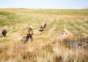 A group of people walking across a grassy hillside.