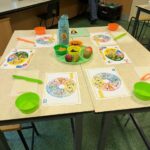 Table with a variety of fruits, with chopping boards to explore and the eatwell guide sheets.