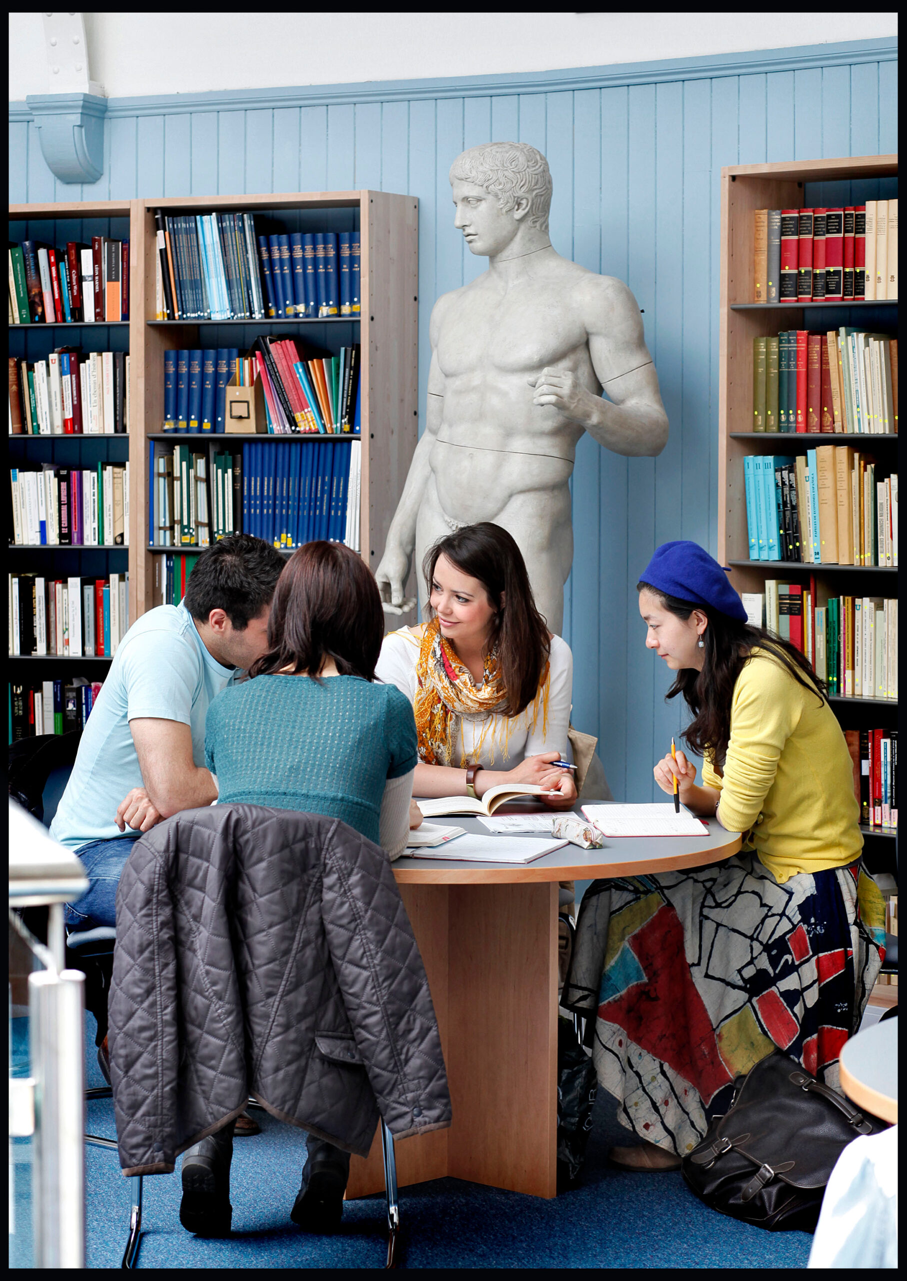 three students sit at a table in the library