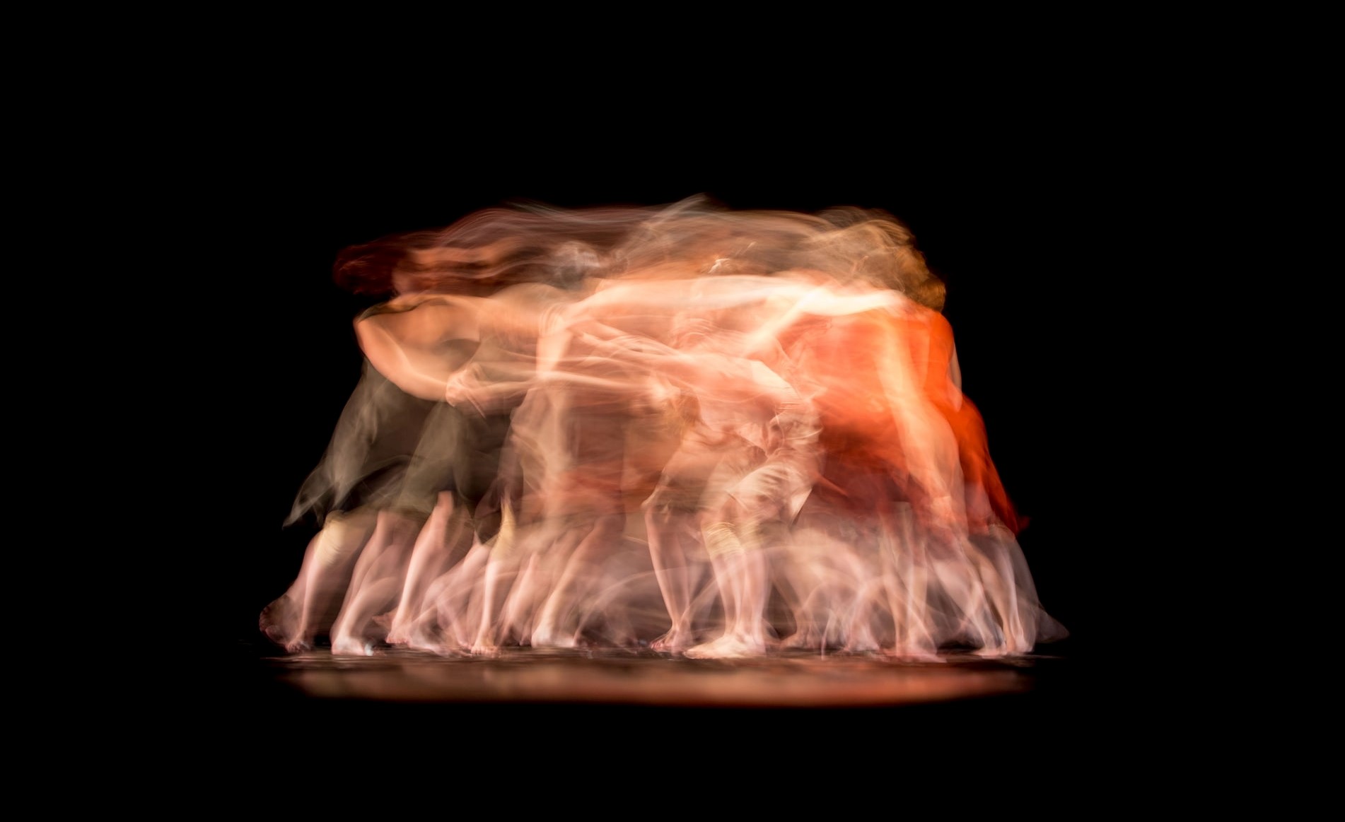 Blurry photo of dancers in black background.