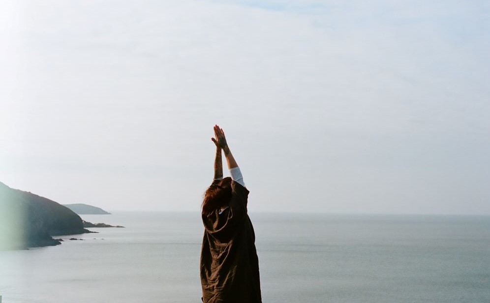 Person doing yoga while facing ocean.